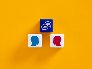 Two heads and speech bubbles discussing on colorful blocks