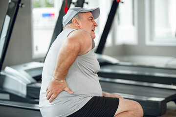 Man with low back pain in gym. Sports exercising injury. healthcare and lifestyle concept