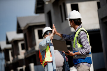 Construction team members wearing hard hats share a high five