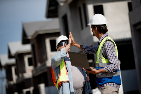 Construction team members wearing hard hats share a high five