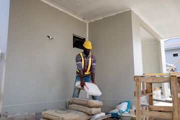 Worker is unloading the bags of cement an apartment is under construction, remodeling, renovation,...
