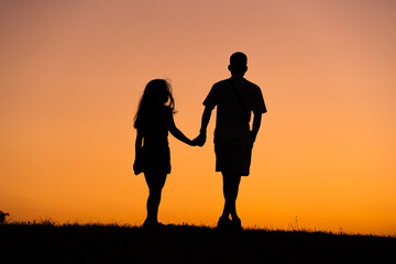 Pareja caminando al atardecer en silueta 