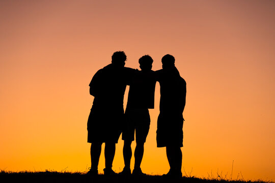 Grupo de amigos abrazándose al atardecer silueta 