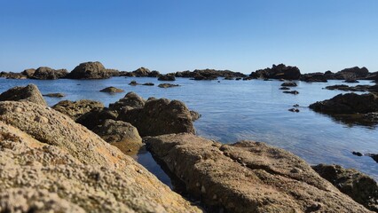 The Gondarem Beach in Foz do Douro, Porto, Portugal. Calm tide over rocky coastline and coarse sand, perfect for resting and relaxing in the summer by the Atlantic shore.