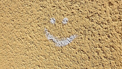 uśmiech narysowany na pomarańczowej ścianie biała kredą