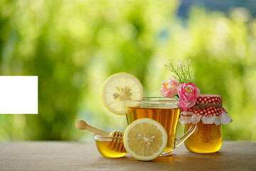Honey in a glass jar and lemon with green background