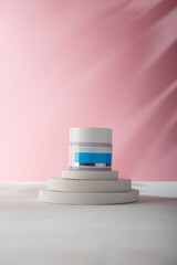 White blue cream jar with no brand, blank label mock-up on concrete stairs stand, pink background. Product advertising banner, copy space