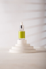Dropper bottle with blank green label, no brand template. Cosmetics mockup jar on concrete decorative stand, white backdrop. Copy space. Beauty product