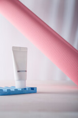 Cosmetics tube mockup on concrete stand, pink paper roll on white background. Unbranded beauty container, no label template. Advertising banner, copy space