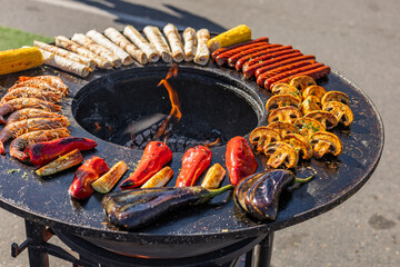 Variety of food being cooked on a grill. The food includes shrimp, corn on the cob, and flatbreads,...
