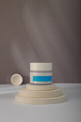 White blue cream jar with no brand, blank label mock-up on concrete stairs stand, grey background. Product advertising banner, copy space
