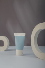 White blue Cosmetics tube mockup, concrete decor on grey background. Unbranded beauty container, no label template. Copy space