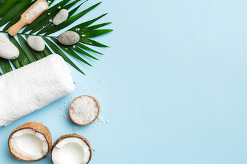 Coconut with jars of coconut oil and cosmetic cream on colored background. Top view. Free space for your text. Natural spa coconut cosmetics and organic treatment concept Coconut Spa composition
