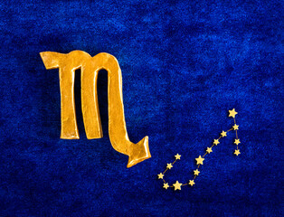 Top view golden zodiac sign Scorpio on blue velvet background