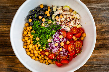Buddha bowl - fresh vegetable salad with chickpea, sliced chicken breast on wooden table	