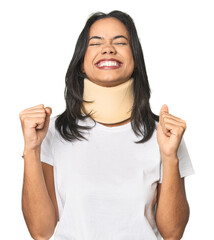 Latina with neck brace in studio celebrating a victory, passion and enthusiasm, happy expression.