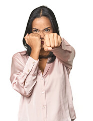 Simple portrait of a young Latina throwing a punch, anger, fighting due to an argument, boxing.