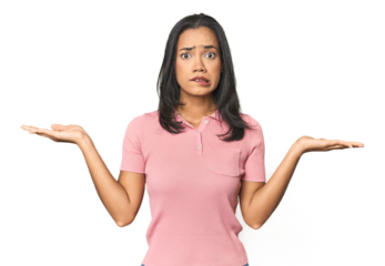 Simple portrait of a young Latina confused and doubtful shrugging shoulders to hold a copy space.