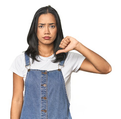 Simple portrait of a young Latina showing a dislike gesture, thumbs down. Disagreement concept.