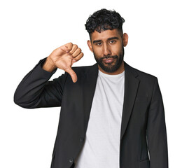 Hispanic businessman in suit in studio showing a dislike gesture, thumbs down. Disagreement concept.