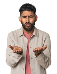 Young Hispanic man isolated folding lips and holding palms to send air kiss.
