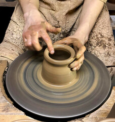 Hands of master shape clay pot on a potters wheel. Closeup.