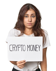 Middle Eastern woman with crypto sign shrugs shoulders and open eyes confused.