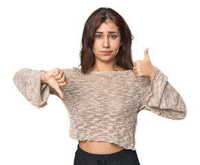 Middle Eastern woman in studio showing thumbs up and thumbs down, difficult choose concept