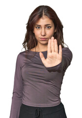 Middle Eastern woman in studio standing with outstretched hand showing stop sign, preventing you.