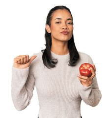 Young Filipina holding a tomato feels proud and self confident, example to follow.