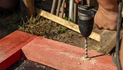 A person is using a drill to make a hole in a piece of wood. The drill is making a hole in the wood...