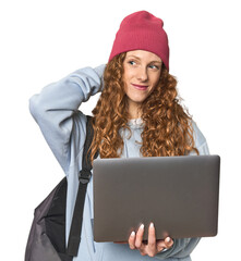 Redhead young woman student with laptop touching back of head, thinking and making a choice.