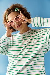 Young woman embraces vibrant fashion with stylish accessories against a blue backdrop