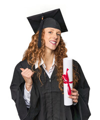 Graduate redhead with diploma points with thumb finger away, laughing and carefree.