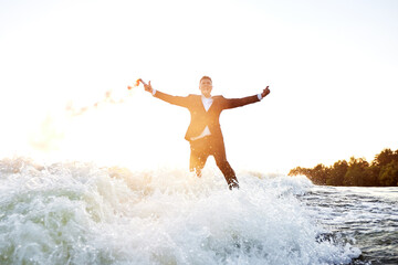 Young man surfer in classic suit rides on the wave. Happy clerk escaped from stuffy office to take...