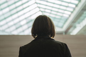 Rear view of businesswoman in bright corporate office building interior