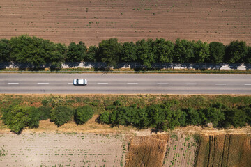 Drone pov of countryside road with single gray automobile, aerial shot