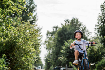 Fototapeta premium A beautiful 6-year-old boy riding a bicycle in a protective helmet outside. A happy child engaged in an active sport. Protection. Life insurance and child safety.