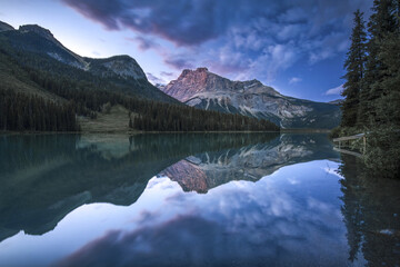 View of the majestic mountains reflecting on the pristine lake under the blue and purple dusk sky, Emerald Lake, British Columbia, Canada.