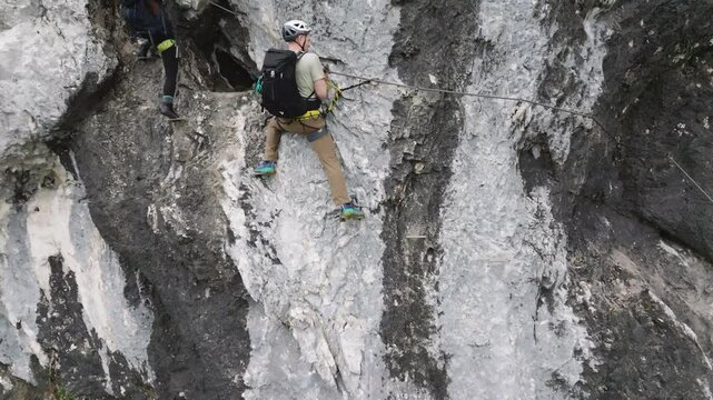Group of climbers on a route, on a rock with belay via ferrata. Drone view of people in equipment