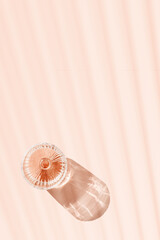 Minimal style glass of rose wine or champagne on pastel pink with shadows and light reflections. Bright shine wineglass with sparkling alcohol drink at sunlight, aesthetic lifestyle summer beverage
