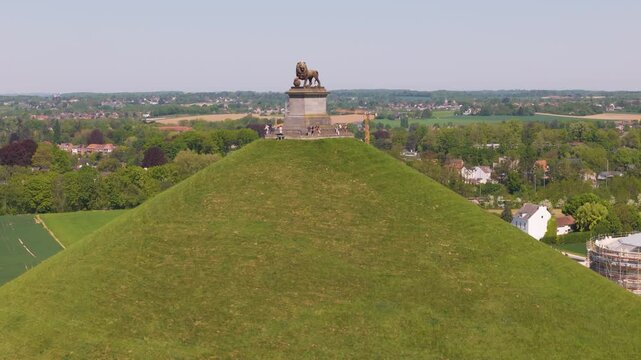 visitors atop stairs platform surrounded by green grass mound lion's waterloo belgium both monument's angle upward drone shot leeuw van lush scale natural 