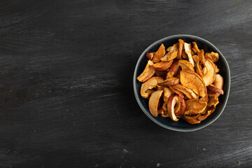 Dried Apples in ceramic bowl on black wooden. Top view, copy space
