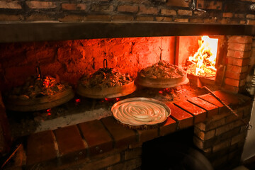 Spiral burek pie ready for baking under sač lids in a traditional wood-fired oven. Rustic Balkan...