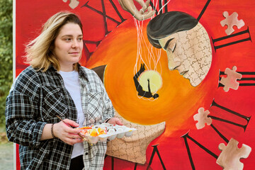 Young woman holding paint palette stands by vibrant surreal clock painting with puzzle patterns....