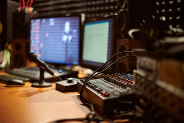 Audio mixing console with microphone in contemporary recording studio setting, showcasing intricate connections and advanced technology used in sound production