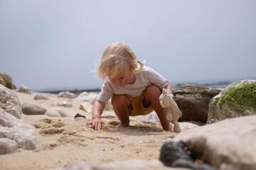 4-year-old European girl searching for seashells on the beach