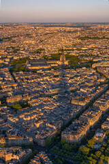Fototapeta premium Aerial view of the Invalides Palace and Parisian rooftops during the Golden Hour with the Eiffel Tower's shadow cast on the buildings and monuments at sunset.