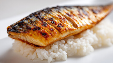 Grilled mackerel fillet with crispy skin served on bed of white rice, showcasing delicious and appetizing meal