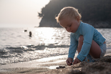 Toddler girl playing in the sand by the water on the beach
